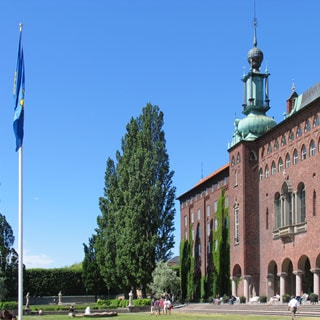 На фото: часть фасада знаменитой Стокгольмской городской ратуши со стороны набережной, прилегающая территория - газон, дорожки, деревья