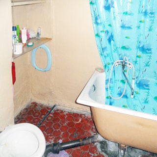 На фото: часть помещения совмещенного санузла, унитаз, ванная со смесителем, полы - плитка, стены окрашены
