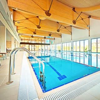 На фото: бассейн в помещении СПА центра, четыре дорожки, панорамные окна во всю стену, светло и просторно