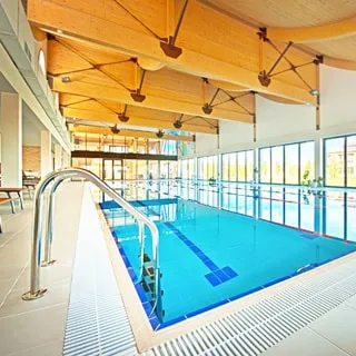 На фото: бассейн в помещении СПА центра, четыре дорожки, панорамные окна во всю стену, светло и просторно