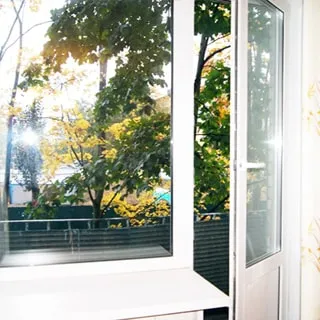 На фото: балконный блок - дверь и одностворчатое окно, стеклопакет, дверь на балкон приоткрыта, балкон не остеклен, за балконом на улице - деревья