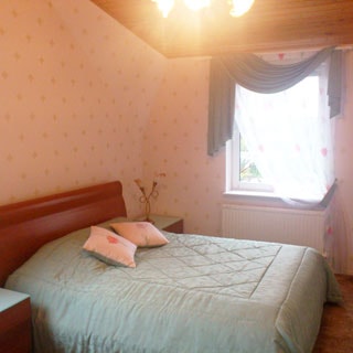 На фото: внутреннее помещение - спальня, разноуровневый потолок, двуспальная застеленная кровать, две прикроватные тумбочки, окно