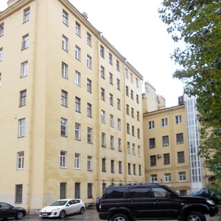 На фото: фасад семиэтажного жилого дома со стороны двора, классический оштукатуренный фасад, без балконов и элементов декора, придомовая территория асфальтирована, высажены, деревья, припаркованы автомобили