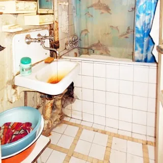 На фото: часть помещения ванной комнаты, прямо у стены - ванная со смесителем, слева от нее - керамическая раковина на кронштейнах со своим смесителем, полы и стены у ванной облицованы керамической плиткой