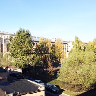На фото: вид из окна в зеленый большой двор, газон, деревья, огороженная спортивная площадка, на придомовой территории - припаркованные автомобили