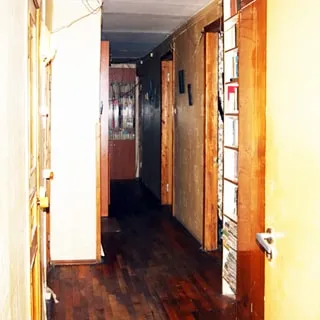 На фото: часть помещения коридора и прихожей, полы - паркет, слева - входная дверь, справа - двери в соседние помещения, спрва у стены - книжный стеллаж, на дальнем плане в конце коридора - книжный шкаф