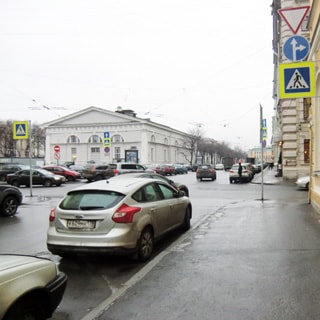 На фото: городская перпектива, улица, тротуар, дорожные знаки, припаркованные автомобили, пешеходы, слева впереди - здание Манежа, за ним деревья Александровского сада, еще дальше - часть здания Генерального штаба на Дворцовой площади