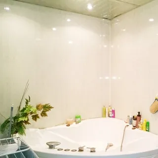 На фото: часть помещения санузла с большой угловой ванной типа джакузи, на потолке - точечные светильники, стены и потолок облицованы сайдингом