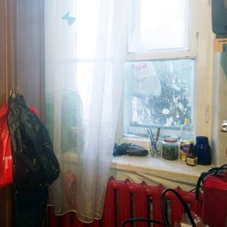На фото: часть помещения жилой комнаты, большое двустворчатое окно во двор, под окном - радиатор центрального отопления, слева от окна - платяной шкаф
