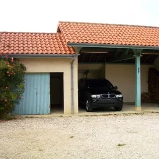 На фото: гараж на две легковые автомашины, слева пристройка со сдвижной дверью, кровля - черепица, дворовая территория перед гаражом отсыпана гравием