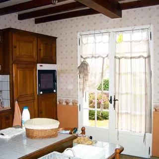 На фото: часть помещения кухни, на переднем плане - обеденный стол со стульями, на заднем плане - встроенная кухонная мебель, встроенный духовой шкаф, застекленная верандная дверь с выходом на террасу