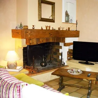 На фото: часть помещения гостиной, камин, у камина - журнальный столик, телевизор, мягкая мебель, полы - плитка