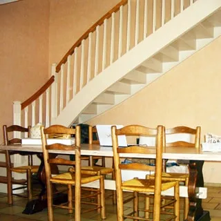На фото: часть помещения гостиной, стол со стульями, лестница на второй этаж, полы - плитка