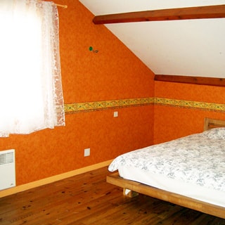 На фото: часть помещения мансардного этажа, двуспальная кровать, окно, полы - дощатые