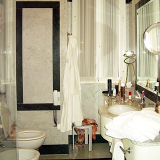 На фото: часть помещения совмещенного санузла, справа умывальник с большой рабочей поверхностью и зеркалом во всю стену, слева - унитаз, биде