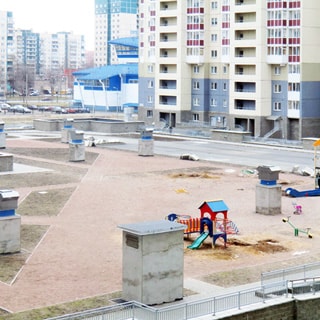 На фото: вид из окна во двор, на кровле подземного паркинга - детская площадка, газоны, вентиляционные выходы, территория огорожена металлическим ограждением