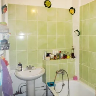 На фото: часть помещения ванной комнаты, керамическая раковина на стойке со смесителем, ванная со смесителем, стены облицованы салатовой керамической плиткой