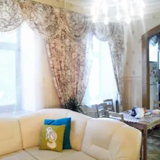 На фото: часть просторной светлой комнаты, два окна, мягкий диван, обеденный стол со стульями, на потолке - люстра