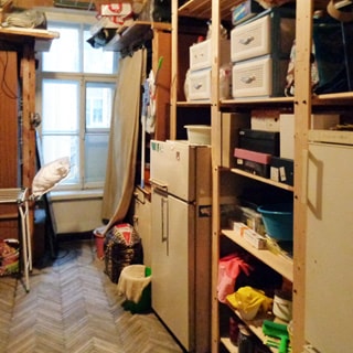 На фото: помещение кладовой, одно окно, справа и слева от окна - стеллажи и шкафы с вещами, два двухкамерных холодильника, полы - паркет.