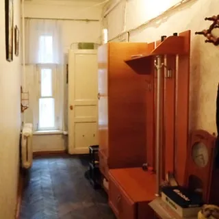 На фото: коридор-прихожая, одно окно, слева на стене - батарея центрального отопления, справа одежные шкафы и вешалки, входная дверь, полы - паркет.