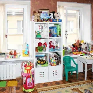 На фото: комната, два окна, на окнах - стеклопакеты, две батареи центрального отопления, детская мебель, игрушки, полы - линолеум