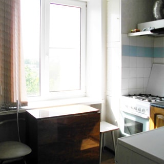 На фото: кухня, окно со стеклопакетом, плита - газовая, над плитой - вытяжка, кухонный раскладной стол-книжка, стул, табурет, стены облицованы плиткой