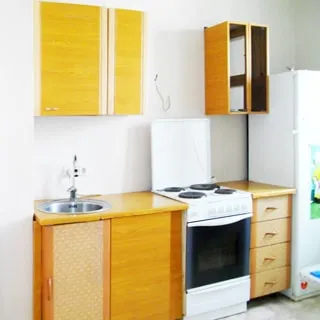 На фото: часть кухни, столы-тумбы и навесные шкафы, электрическая кухонная плита с духовкой, металлическая мойка со смесителем, двухкамерный холодильник