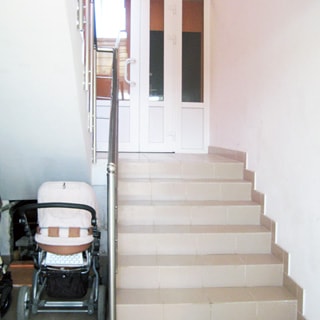 На фото: лестничный пролет от входа в подъезд до первого этажа, стены - окрашены, полы и ступени - плитка, под лестницей - колясочная, перила - стальные