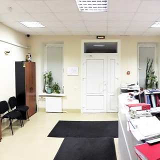 На фото: часть помещения приемной, входная дверь, справа и слева от двери по одному окну, по левой стене шкаф для одежды, стулья для посетителей, по правой стене - стойка администратора, полы - плитка, потолки - подвесные