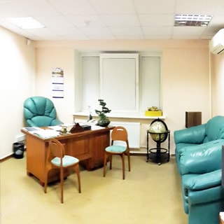 На фото: часть помещения кабинета руководителя, окно, у окна слева письменный стол с офисным креслом, под окном радиатор отопления, справа у стены два мягких кресла, на стене - кондиционер, потолки - подвесные
