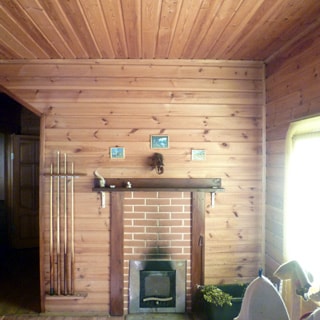 На фото: часть внутреннего помещения, печь, у печи - кадка с банными вениками, справа - окно, стены и потолок - обшиты деревом
