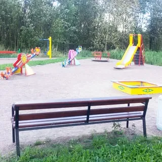 На фото: часть дворовой территории, оборудованная детская площадка, горка, качели, карусель, песочница, скамейка для родителей, вокруг площадки - газон, деревья