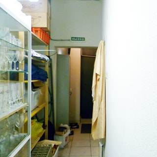 На фото: часть помещения коридора, стены окрашены, полы - плитка, слева вдоль стены - стеллажи для посуды и хозяйственной утвари, на заднем плане - тамбур и дверь запасного выхода