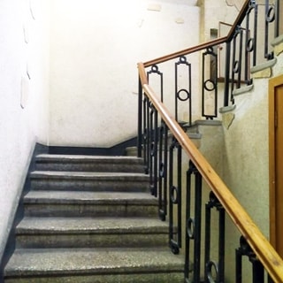 На фото: часть трехмаршевого лестничного пролета между этажами, лестница - бетонная, перила - деревянные по металлическому ограждению, стены окрашены