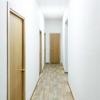 На фото: часть помещения коридора, по левой стене - три двери в помещения, прямо в конце коридора - дверь в помещение, в правой стене проем в соседнее помещение, полы - линолеум, стены - окрашены, потолки - подвесные, установлены офисные потолочные светильники