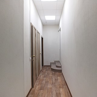 На фото: часть пощения - коридор, по левой стене - три двери, по правой стене в конце коридора - одна дверь с двумя ступеньками вверх, полы - линолеум, стены окрашены, потолки - подвесные, на потолке - светильники дневного света офисного типа