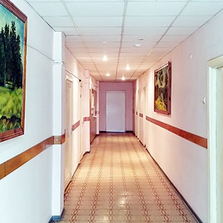 На фото: часть помещения коридора без окон, полы - линолеум, стены - окрашены, потолки - подвесные с точечными светильниками, на стенах - репродукции картин, слева, справа и в дальней стене - двери в соседние помещения