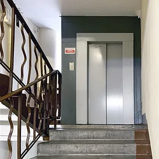 На фото: часть лестничного пролета с лифтом на межэтажной площадке, лифт с автоматическими дверями, слева от лифта на площадке - мусоропровод, лестничные ограждения - металлические, перила - пластиковые, стены и потолок - окрашены