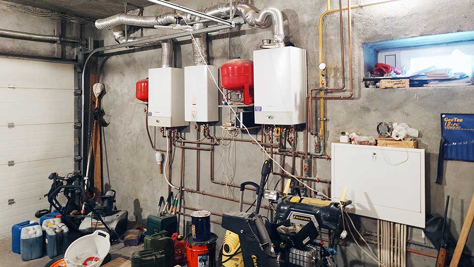 На фото: нежилое помещение с котельным оборудованием и окном, полы - бетонная стяжка, стены - оштукатурены под покраску, слева на всю ширину и высоту помещения - роллетные ворота (закрыты), на дальней стене - газовое отопительное и водогрейное оборудование